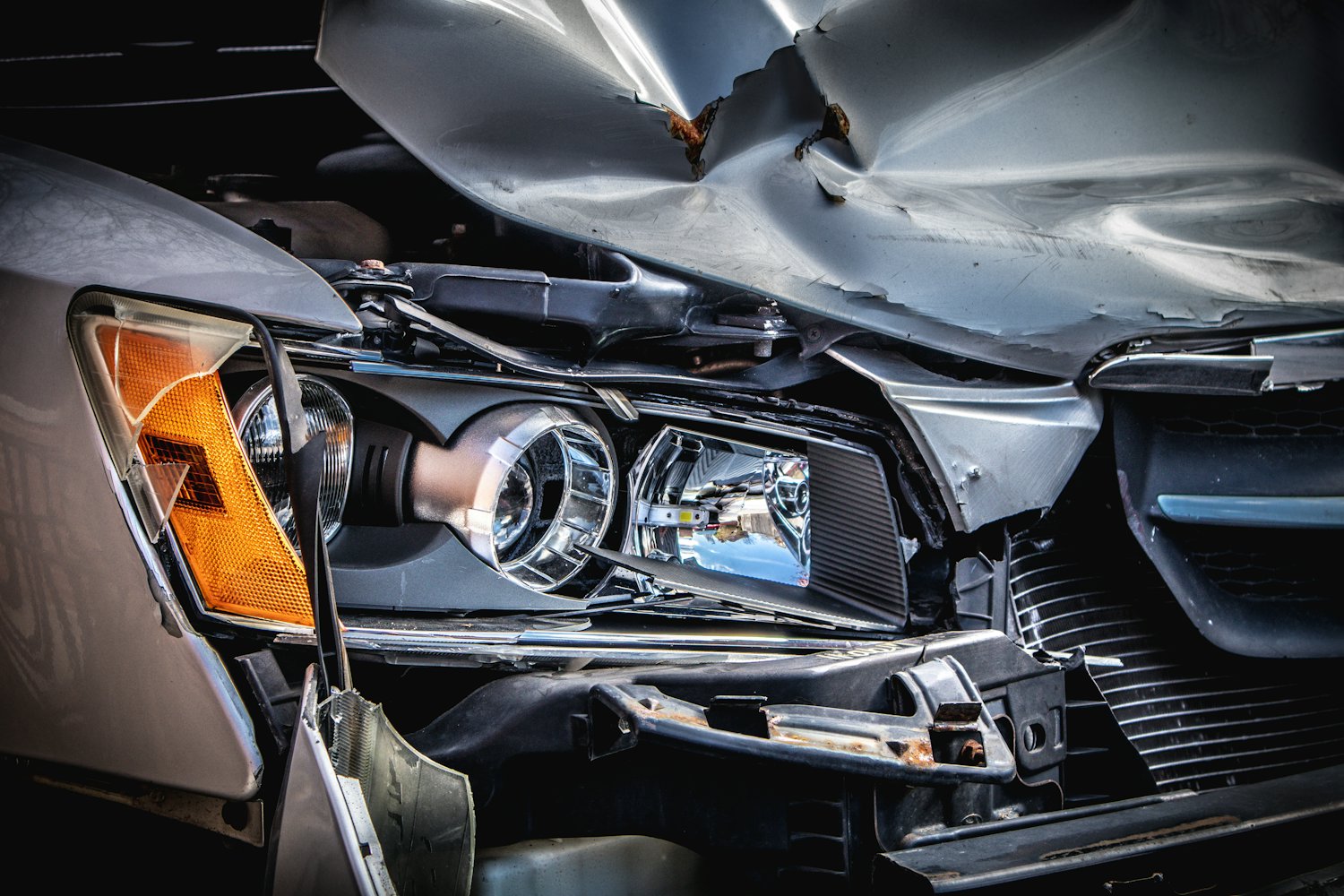 Frontschaden an einem Pkw nach einem Unfall: eingedrückte Motorhaube und zerbrochener Scheinwerfer